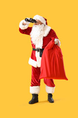 Santa Claus with Christmas bag looking through binoculars on yellow background