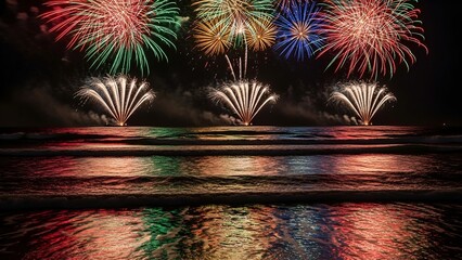 Colorful fireworks burst over ocean waves, reflecting in the water during a night celebration