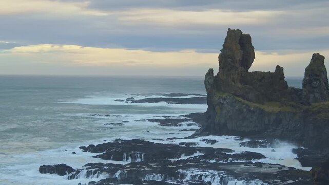 A stunning dolly shot captures the powerful Atlantic ocean waves crashing against the rugged basalt sea stacks of L&oacute;ndrangar on the Sn&aelig;fellsnes Peninsula, Iceland
