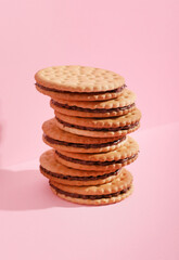 Stack of tasty sandwich biscuits on pink background