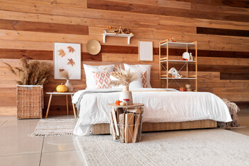 Comfortable bed, shelving unit and wicker basket with pampas grass in interior of bedroom