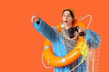 Funny fisherwoman with lifebuoy and binoculars pointing at something on orange background