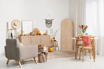 Interior of room with armchair, dining table and autumn decor