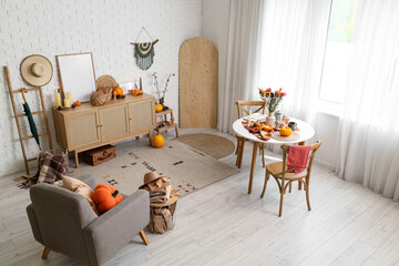 Interior of room with dining table, armchair and autumn decor