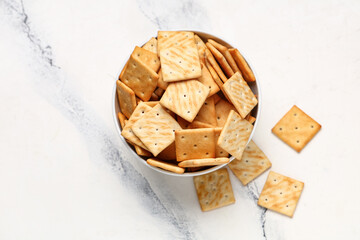 Bowl with tasty crackers on white background