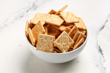 Bowl with tasty crackers on white background, closeup