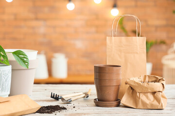 Plant pots with soil and paper bag on table in gardener's workshop