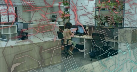Working woman using keyboard and mouse at modern office desk, with laptop dual monitors and plants