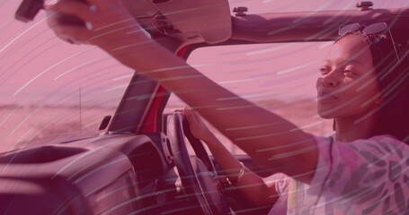 Adjusting mirror, woman driver cruising in red convertible on desert highway, copy space