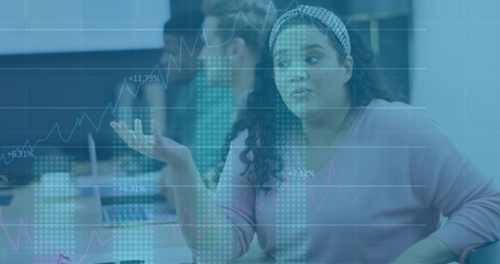 Gesturing mid adult woman wearing pink sweater at conference room meeting with chart overlays