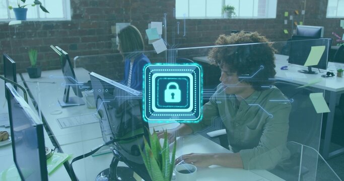 Typing curly-haired man using laptop in open plan office, showing security lock overlay, copy space