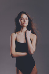 Elegant woman posing confidently in black bodysuit with neutral background, natural lighting, and...