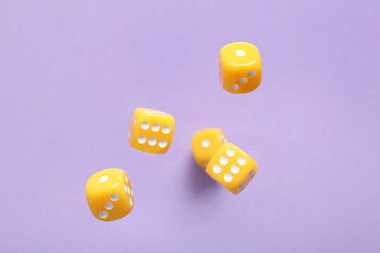 Flying yellow game dices on lilac background