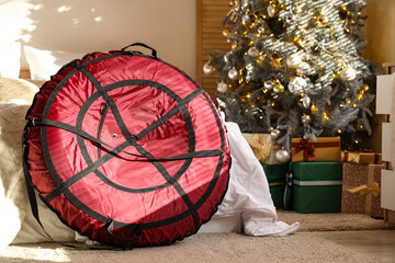 Inflatable sled, comfortable bed and Christmas tree in interior of bedroom, closeup