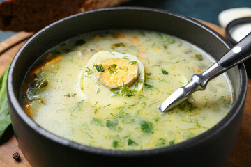 Bowl of tasty green borscht with egg and greens, closeup