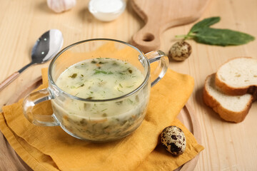 Pot of tasty green borscht with eggs and bread slices on wooden background