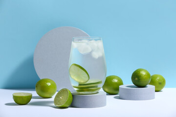 Decorative podium with glass of lime infused water on white table against blue background