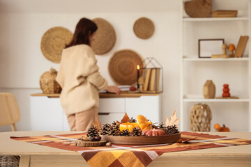 Wooden tray with burning candles and autumn decor on table in interior of living room, closeup