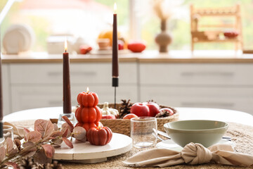 Autumn table setting with burning candles in kitchen, closeup