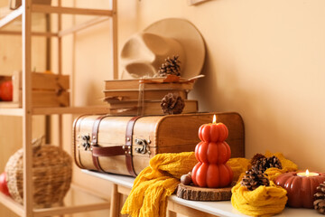 Suitcase, books and burning candles on table in living room