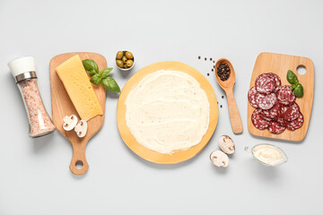 Pizza dough with tasty sauce and ingredients on grey background