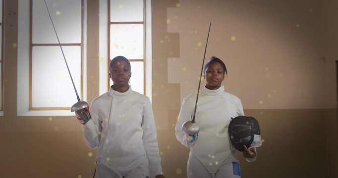 Two female fencers walking into sports hall lowering masks holding epees amid golden sparkles