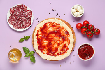 Pizza dough with tasty tomato sauce and ingredients on purple background