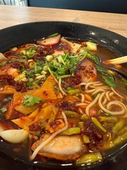 Spicy Asian noodle soup with vegetables and pork in restaurant bowl
