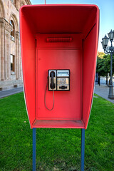 A red phone booth with a phone inside