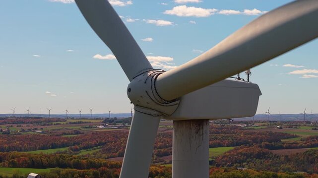 Close-up view of a wind turbine rotor over farmland in upstate New York during autumn, symbolizing renewable energy and sustainability