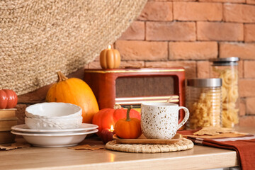 Cup of pumpkin latte with radio and autumn decor on kitchen table at home