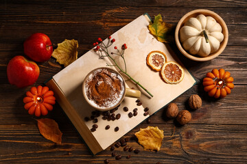 Mug of tasty coffee, notebook and autumn decor on wooden background