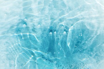 Blue water with ripples on the surface. Defocus blurred transparent blue colored clear calm water surface texture with splashes and bubbles. Water waves with shining pattern texture background.