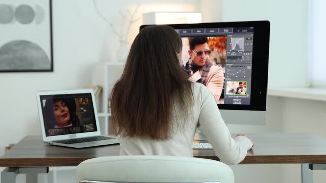 Professional retoucher editing photo on computer and laptop at table in office, back view