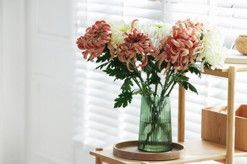 Beautiful chrysanthemum flowers in vase on wooden shelf indoors, space for text