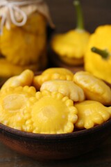Pickled pattypan squashes in bowl on wooden table, closeup