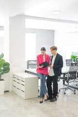 Colleagues look at a folder with documents and discuss work issues. 