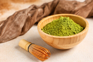 Bowl with powdered matcha tea and chasen on light background