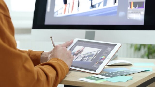 Professional retoucher editing photo on computer and tablet at table in office, closeup