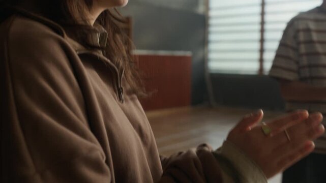 Tilt up of smiling youthful Asian girl clapping hands while standing in front of camera among her schoolmates during successful psychological session