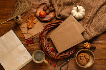 Books with cup of coffee, wreath, sweater and autumn decorations on brown wooden background