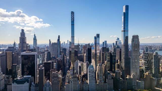 A sprawling cityscape stretches out under a blue sky dotted with fluffy clouds.
