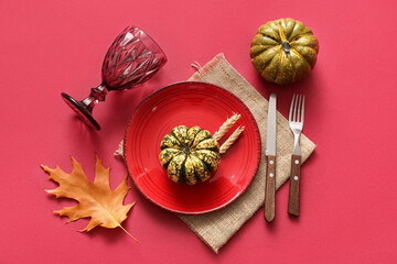 Beautiful table setting with pumpkins, wheat and autumn leaf on red background