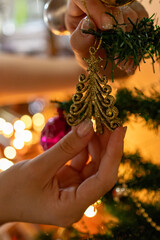 Close up of woman hands decorating christmas tree. Blurred festive background