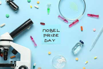Composition with microscope, medicine and NOBEL PRIZE DAY greeting card on blue background. Nobel prize day celebration