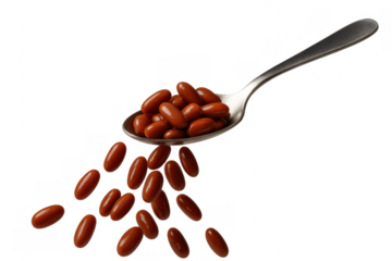 Spoon full of brown capsules falling, representing health, medicine, and nutritional supplements on transparent background