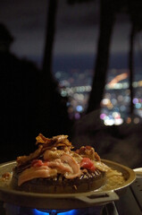 Grilled pork, grilled pork, camping food on the mountain, view of city lights, seen from a high angle