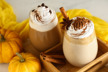 Glasses of hot pumpkin latte with whipped cream and cinnamon on white background