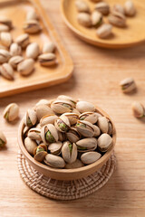Roasted Pistachio nuts in a bowl on wooden background