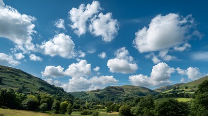 Vibrant white cumulus clouds drift across a deep blue sky above rolling green hills and valleys